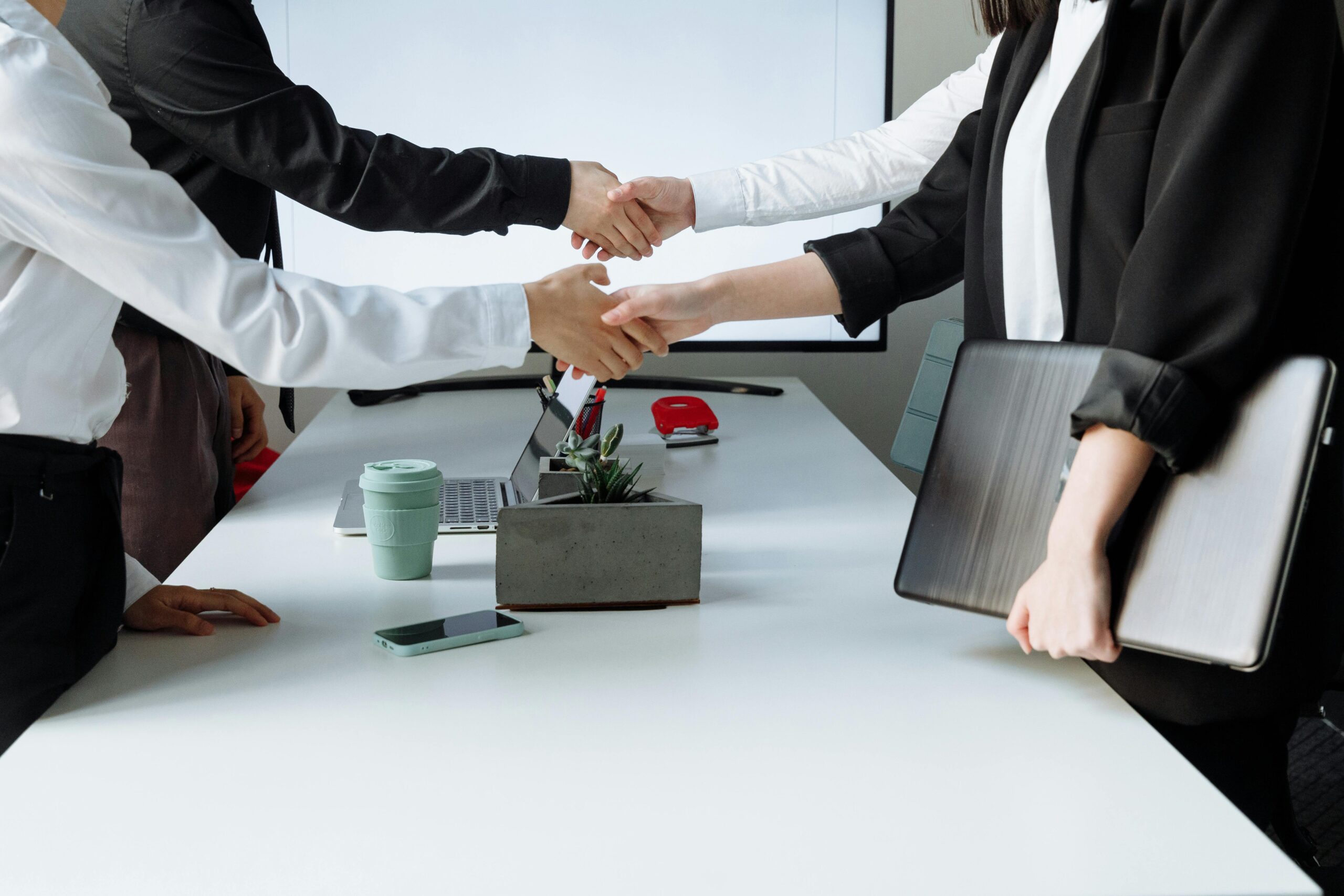 Professionals sealing a deal with a handshake across a conference table during a business meeting.